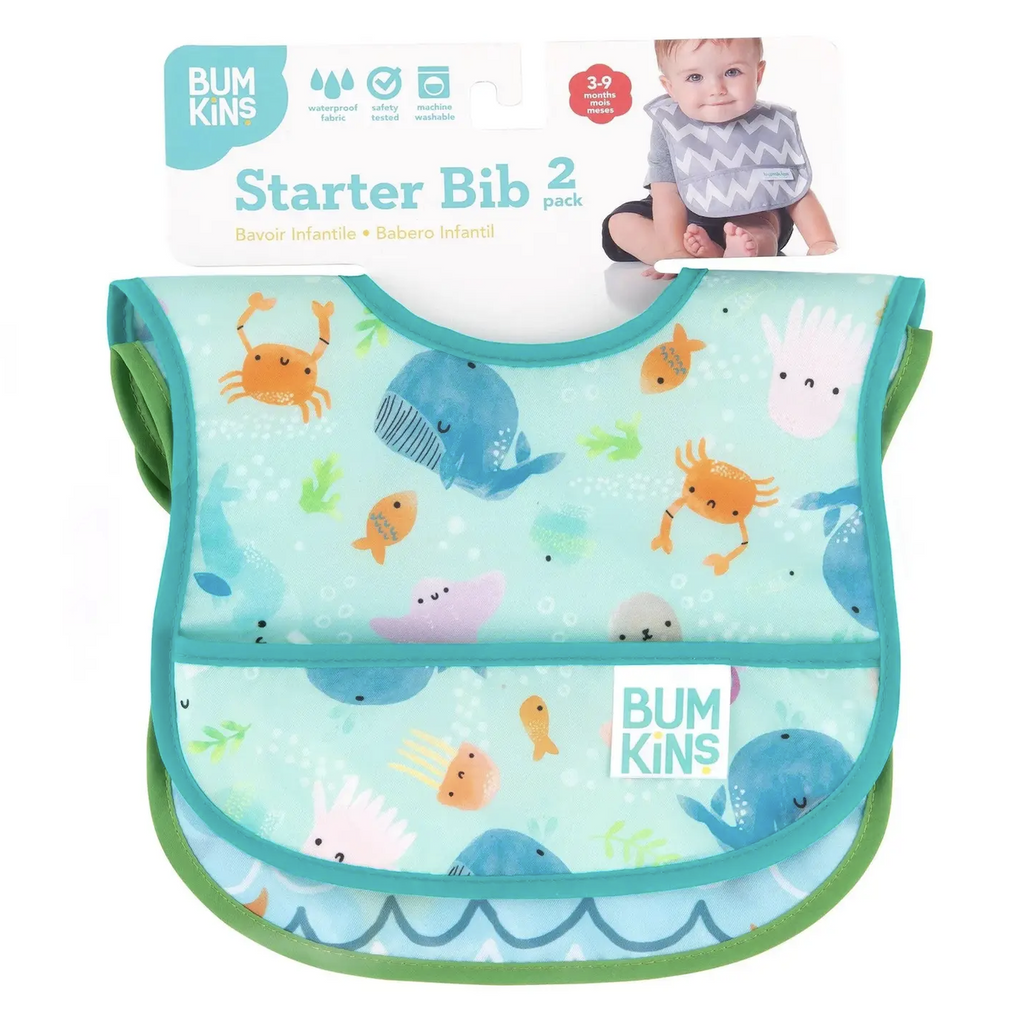 Set of 2 SuperBibs in cute ocean life prints, packaged together hanging on a cardboard hanger The visible bib has orange fish, crabs, whales and other sea animals on a blue background. 