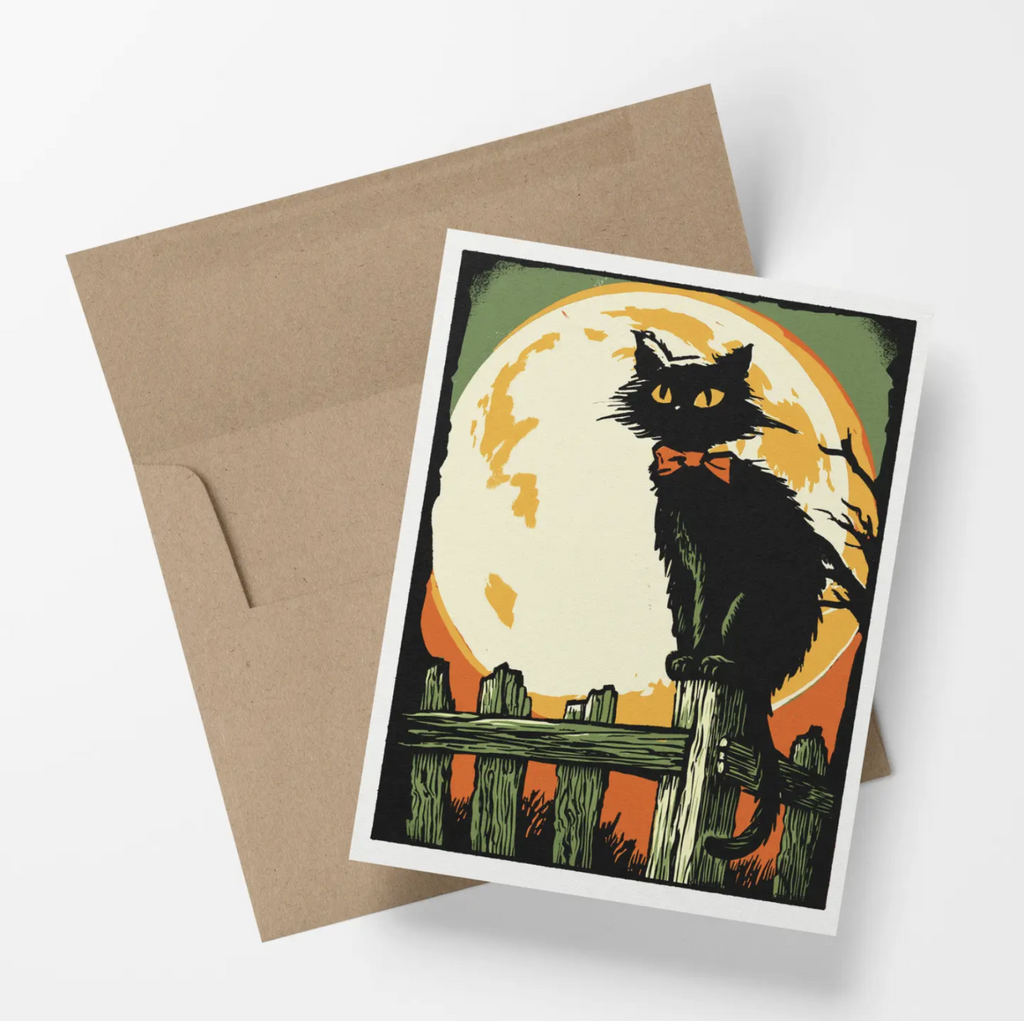 Halloween greeting card featuring a black cat sitting on a wooden fence in front of a full moon.