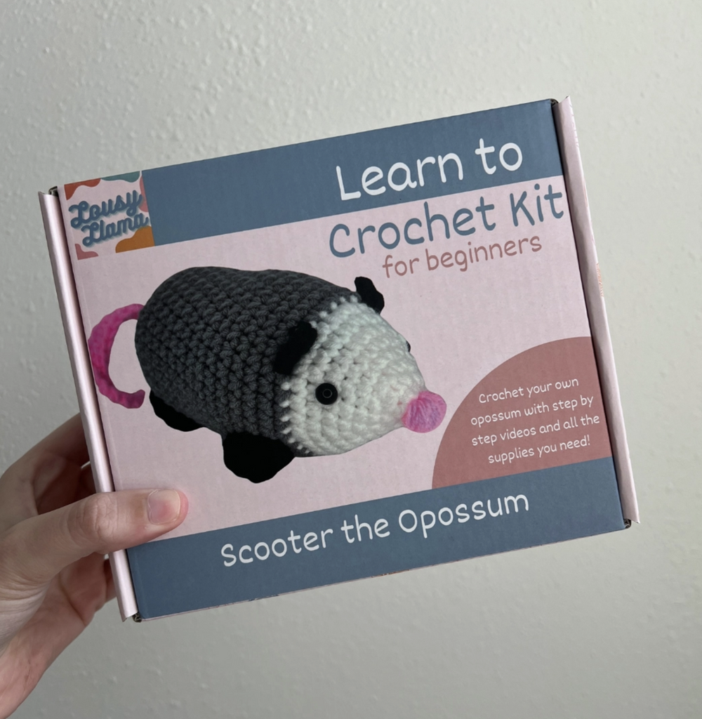 Learn to Crochet Scooter the Opossum for beginners. Crochet your own opossum with step by step videos and all the supplies you need. Crochet possum is grey with black feet and ears, a white face, and pink nose and tail.