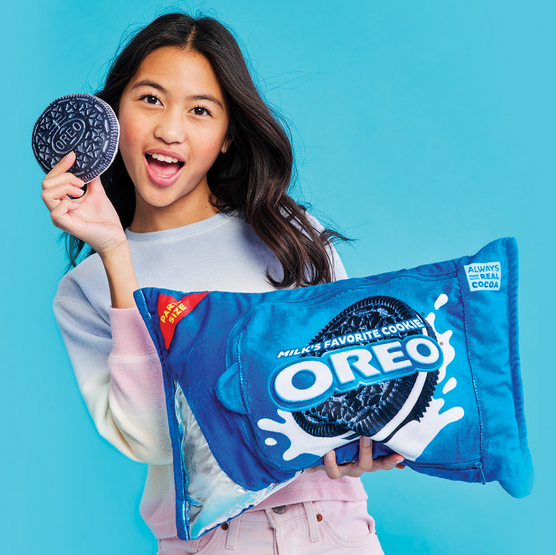 A child holding the Oreo Interactive plush with one of the removeable plush cookies in their other hand. 