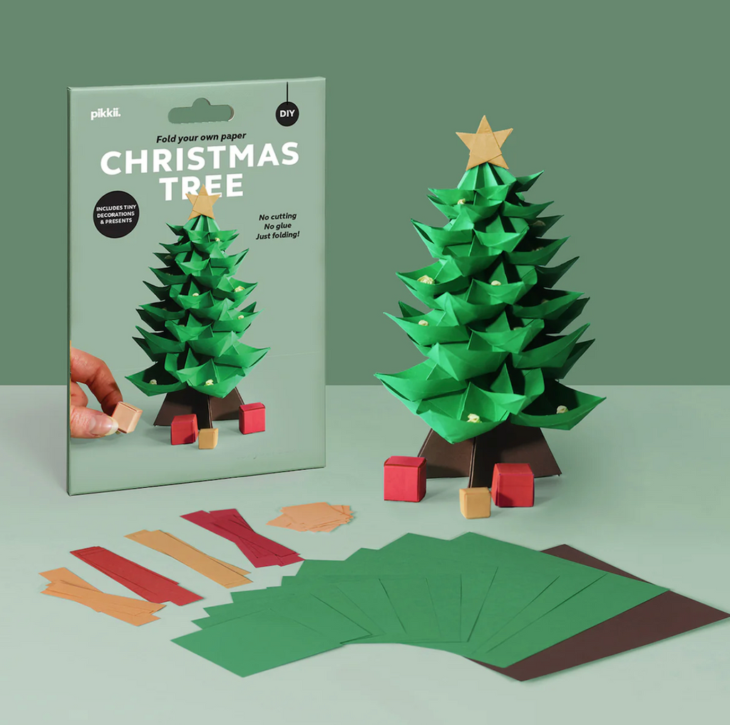 Paper Christmas tree kit with packaging, tree, and pre cut pieces on a green background. 