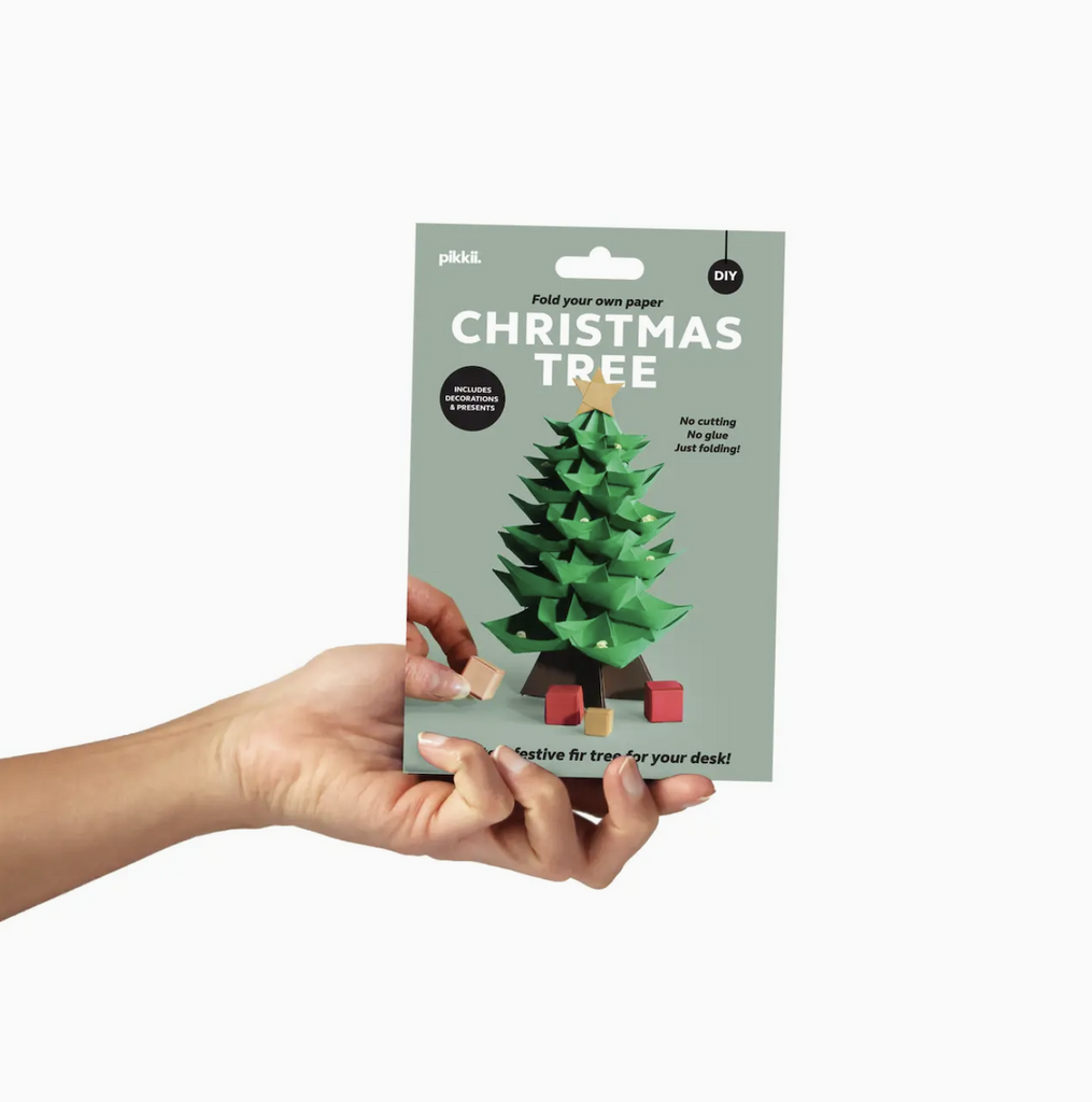 Paper Christmas Tree packaged in a sage green, flat envelope style box that has a picture of the completed tree and presents placed under the tree. 