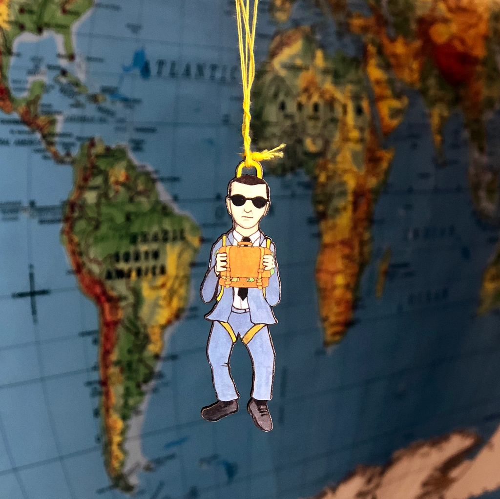 The D.B. Cooper Action Figure suspended from a yellow string in front of a world map. 