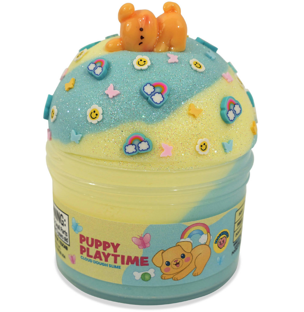A clear container overflowing with yellow and blue cloud dough slime with a puppy charm, and rainbows, butterflies and smiley face mix ins. 