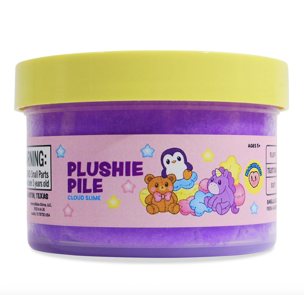 Clear container with a yellow lid that is full of purple slime with a label that has illustrations of a teddy bear, penguin, and unicorn plushies. 