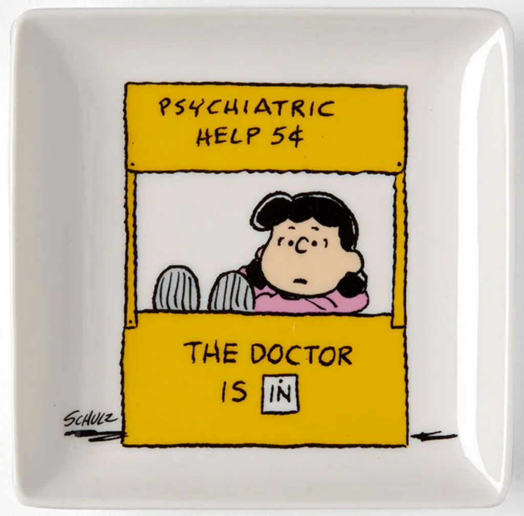 White china trinket tray with illustration from the Peanuts comic of Lucy behind her "Psychiatric Help" desk. 