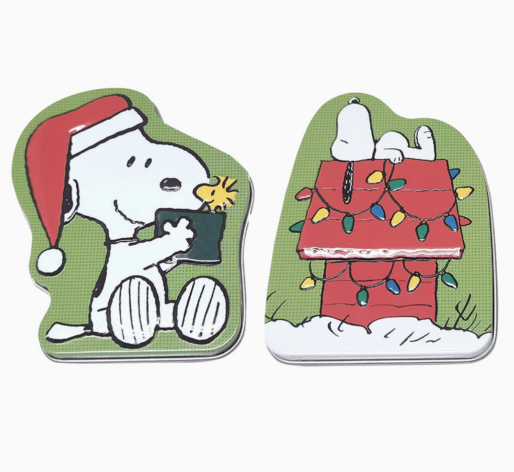 Peanuts themed candy tins. One with Snoopy wearing a Santa hat holding Woodstock and the other one with Snoopy laying on top of his dog house decorated with Christmas lights.  