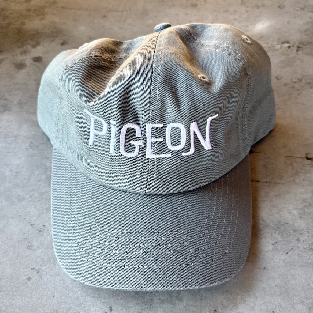 Gray ball cap with "Pigeon" embroidered on the front in white. 