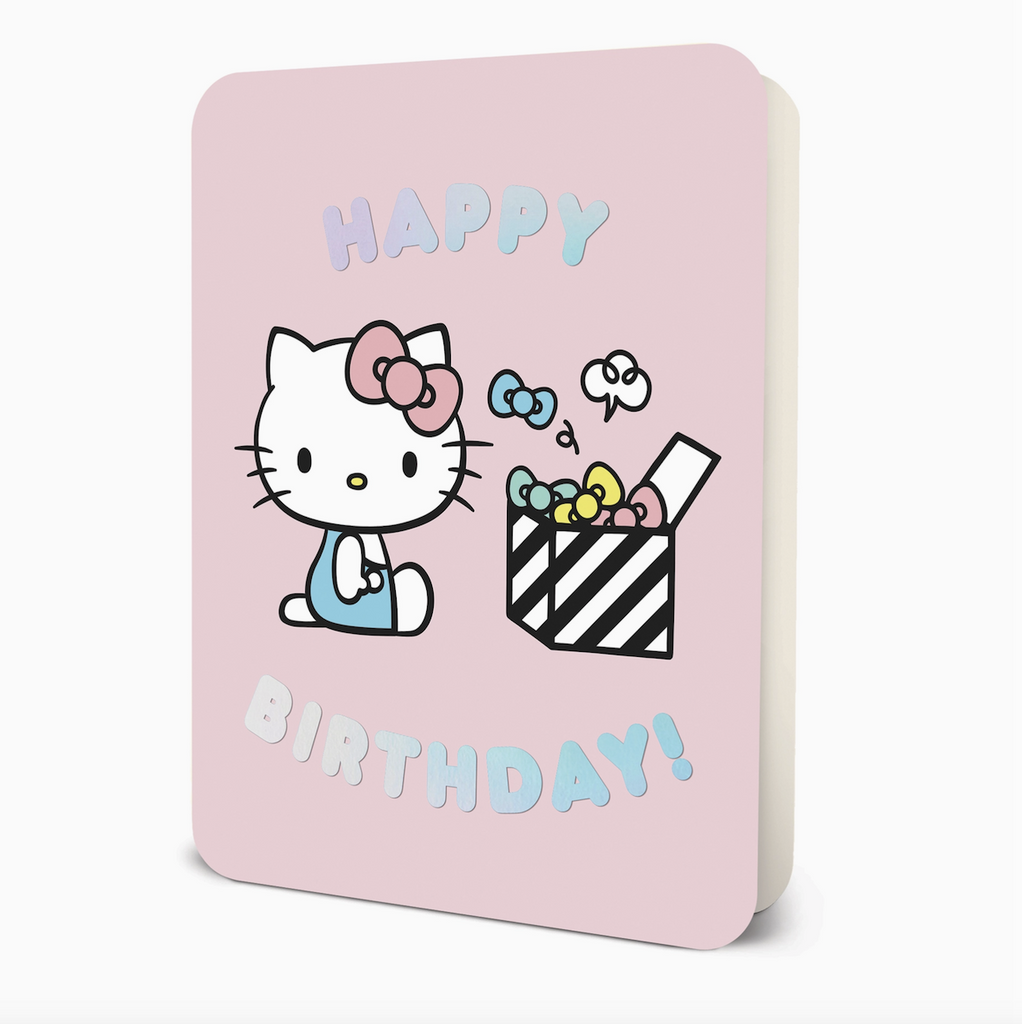 Greeting card with pink background and illustration of Hello Kitty sitting in front of a box of bows that reads Happy Birthday!