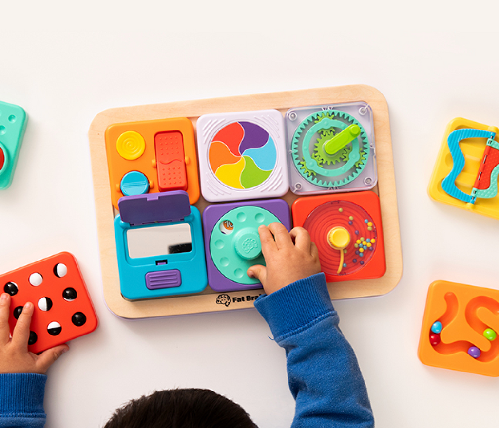 AN overhead view of a toddler playing with the Play Tab Board filled with sensory tiles. 
