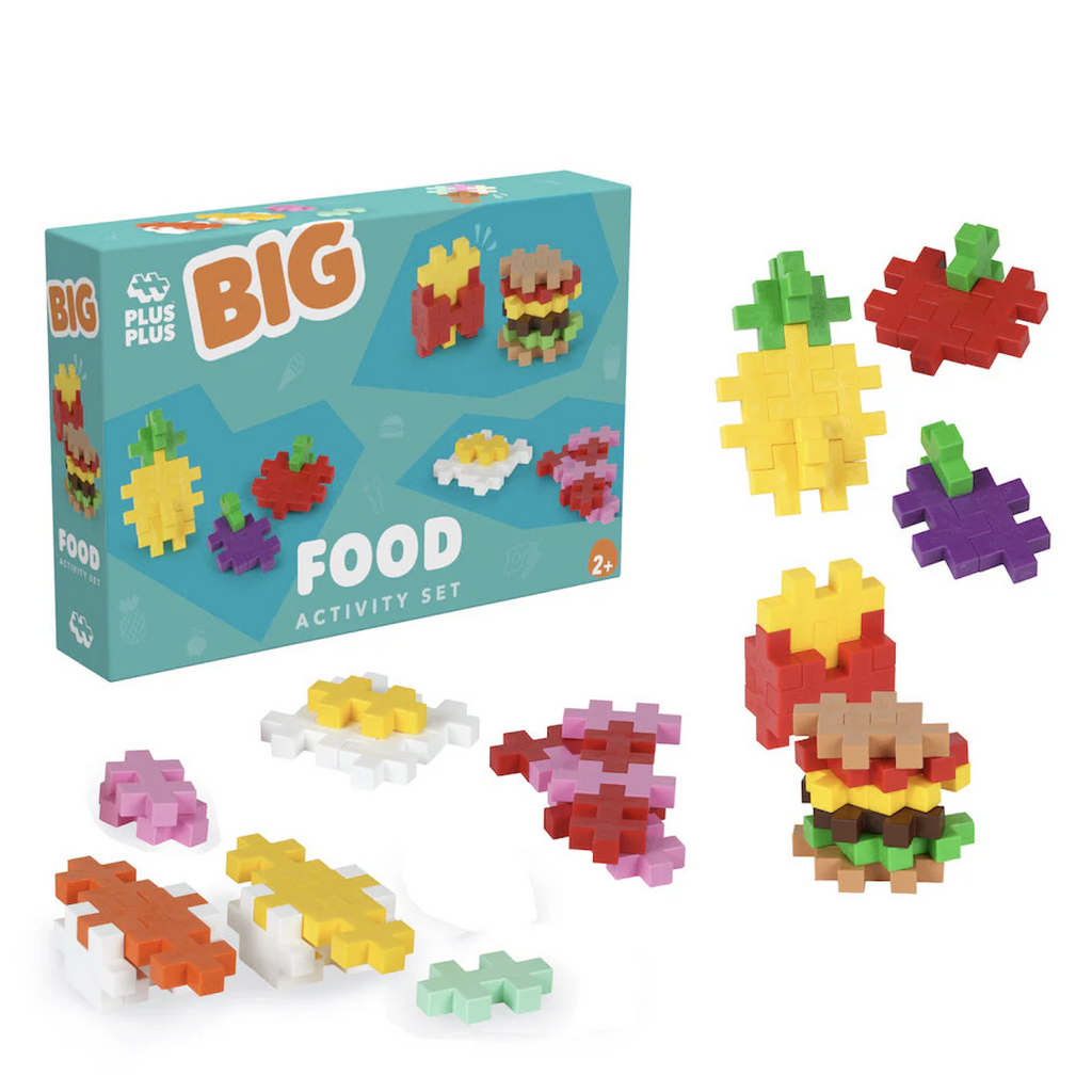 Larger sized colorful Plus Plus pieces fitted together to make food shapes, all placed in front of the blue box they are packaged in . 
