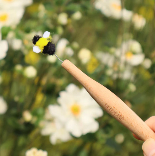 Close up view of the Pollination Wand out of the box being used outside. You can clearly see the felt bee extending from the handle of the wand. 