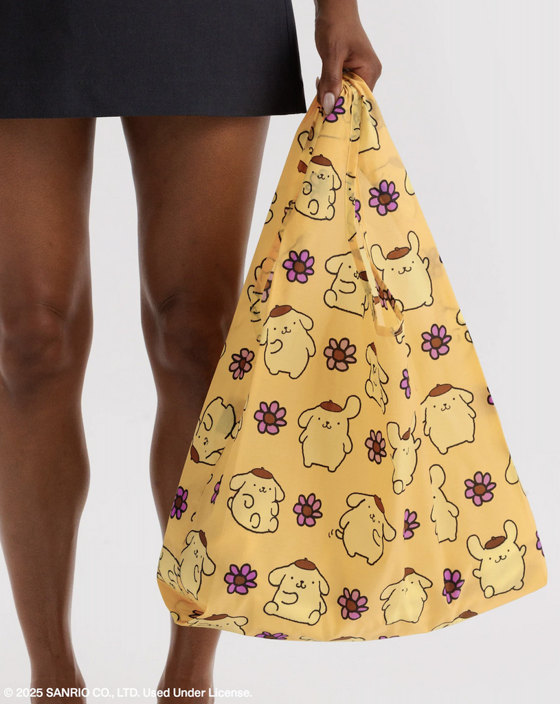 A person holding the Pompompurin standard Baggu reusable shopping bag. 