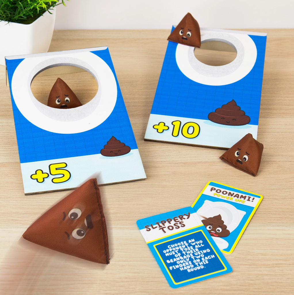 Board game components with poop-themed cards and tokens on a wooden surface