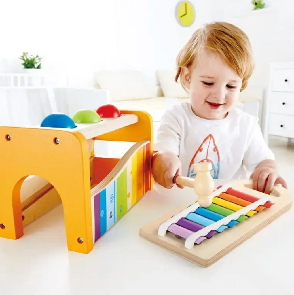 A young child using the hammer to play the xylophone. 