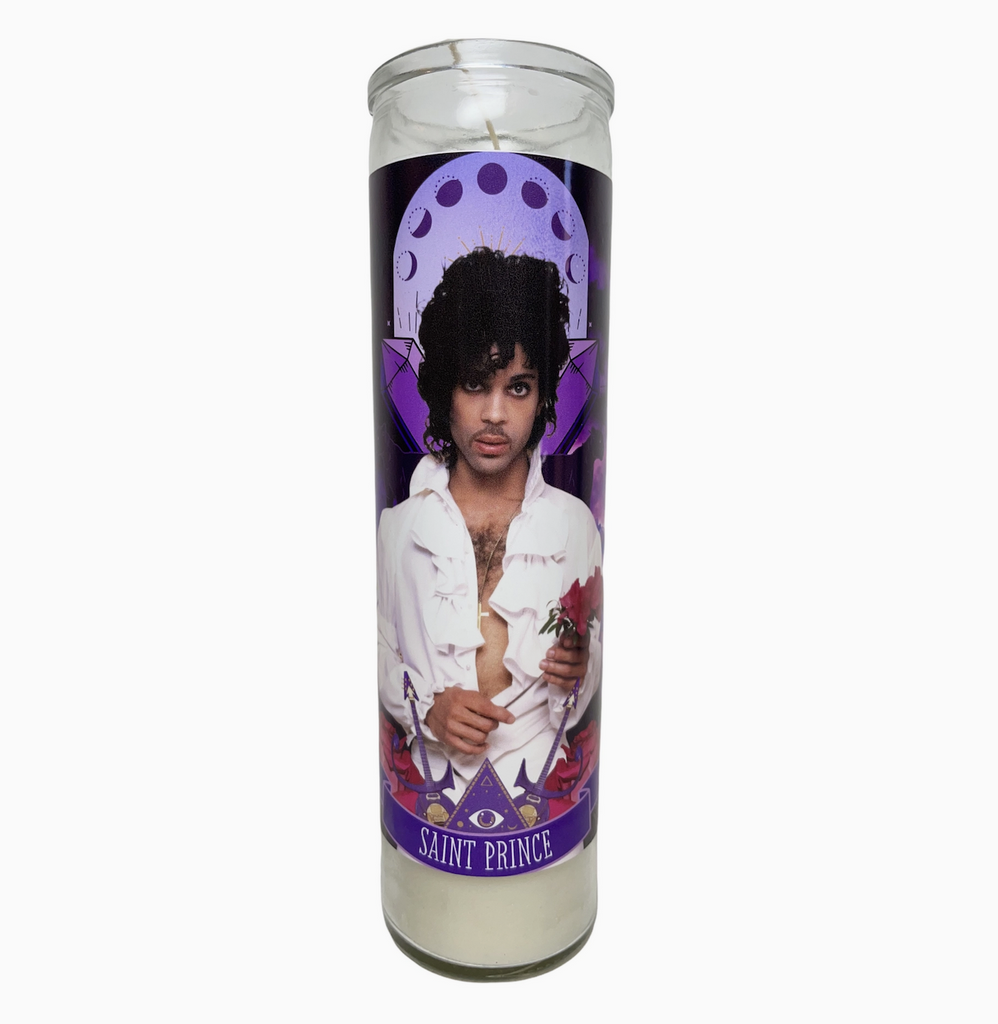 A tall, white altar candle with a picture of Prince wearing a white shirt with ruffles and holding a rose on the front of it. 