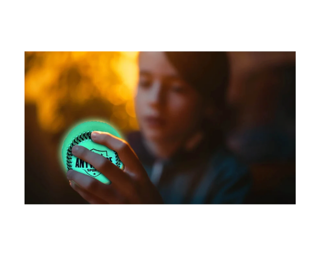 Image of a hand holding a green light up baseball in a dark setting.