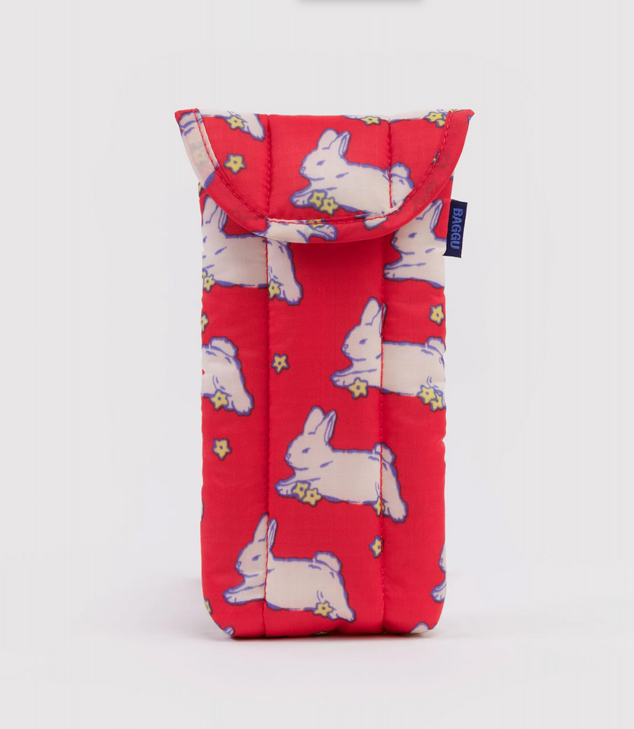 A red glasses case with white bunnies and yellow flowers printed all over it. By Baggu