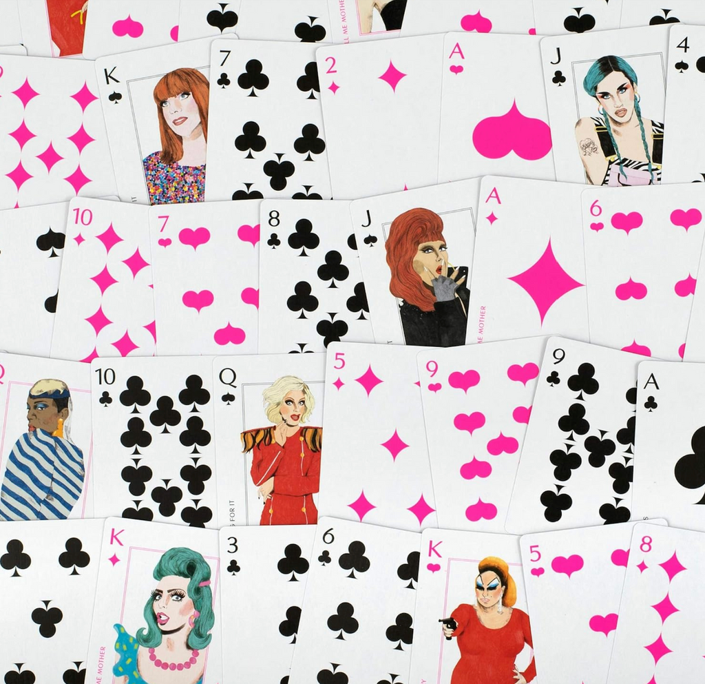 Playing cards turned face up from the Queens! Drag Queen Playing Cards featuring bright pink suits and numbers and illustrations of famous drag queens on the faces of the Jack, Queen, and King cards. 
