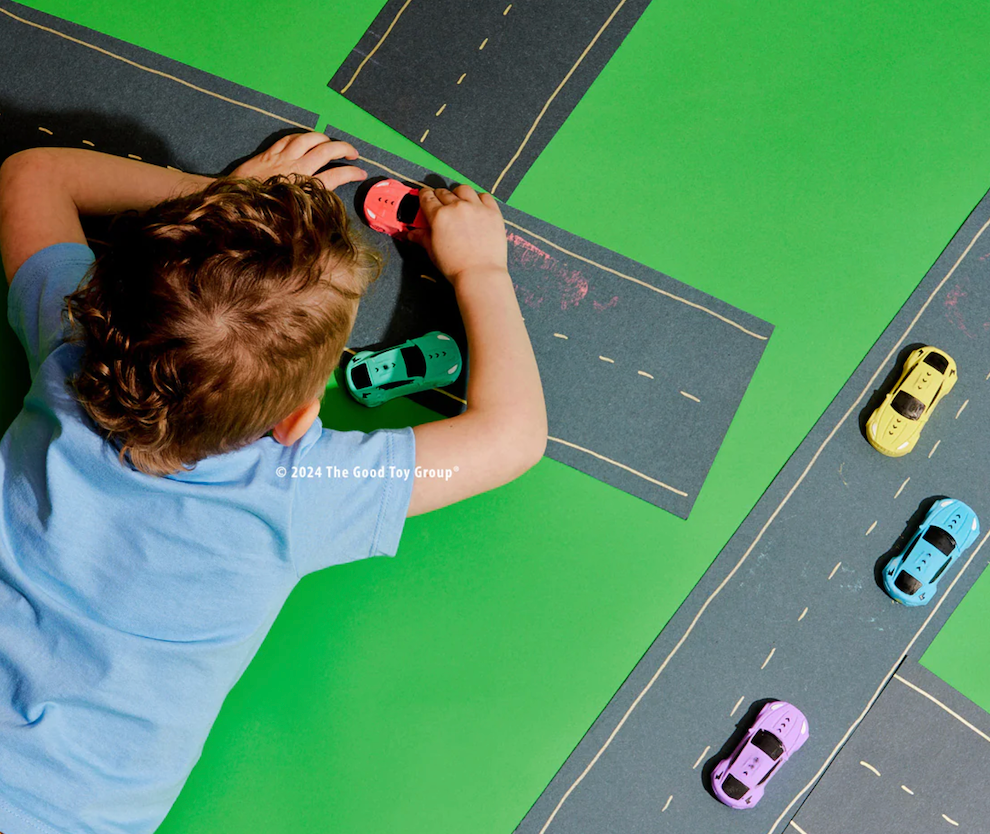 A child playing with the Race Cars Sidewalk Chalk on a chalkboard racetrack. 