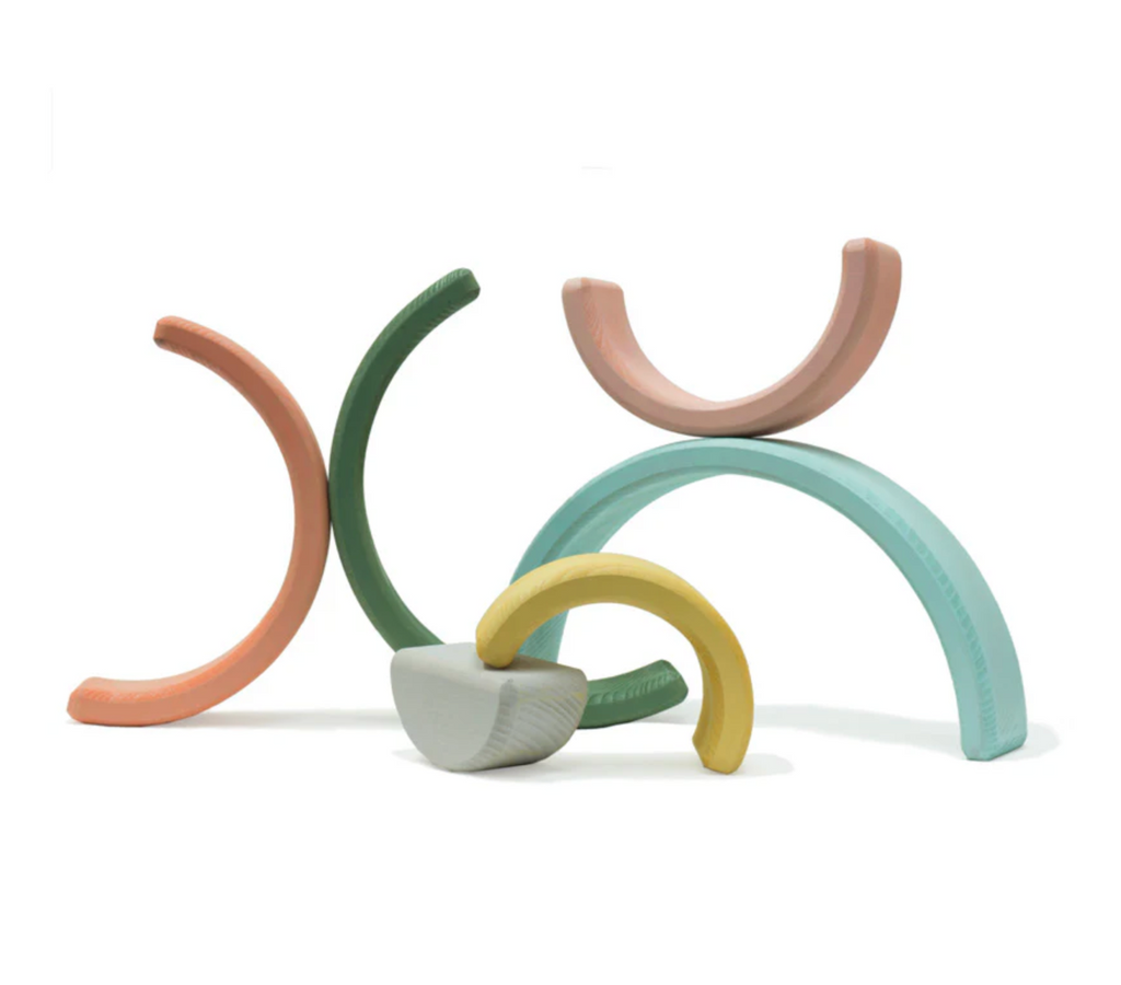 Pastel colored semi circle wooden pieces arranged in stacks on a white background. 