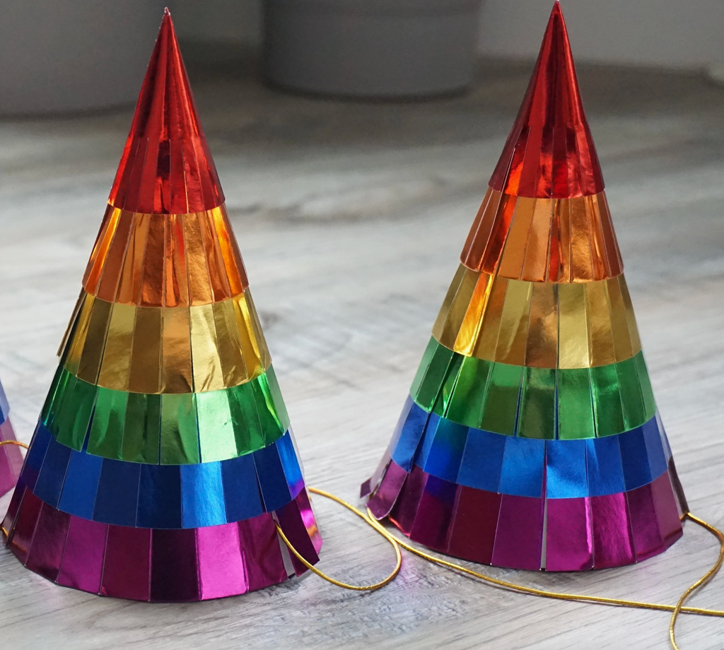 Two rainbow colored party hats. 