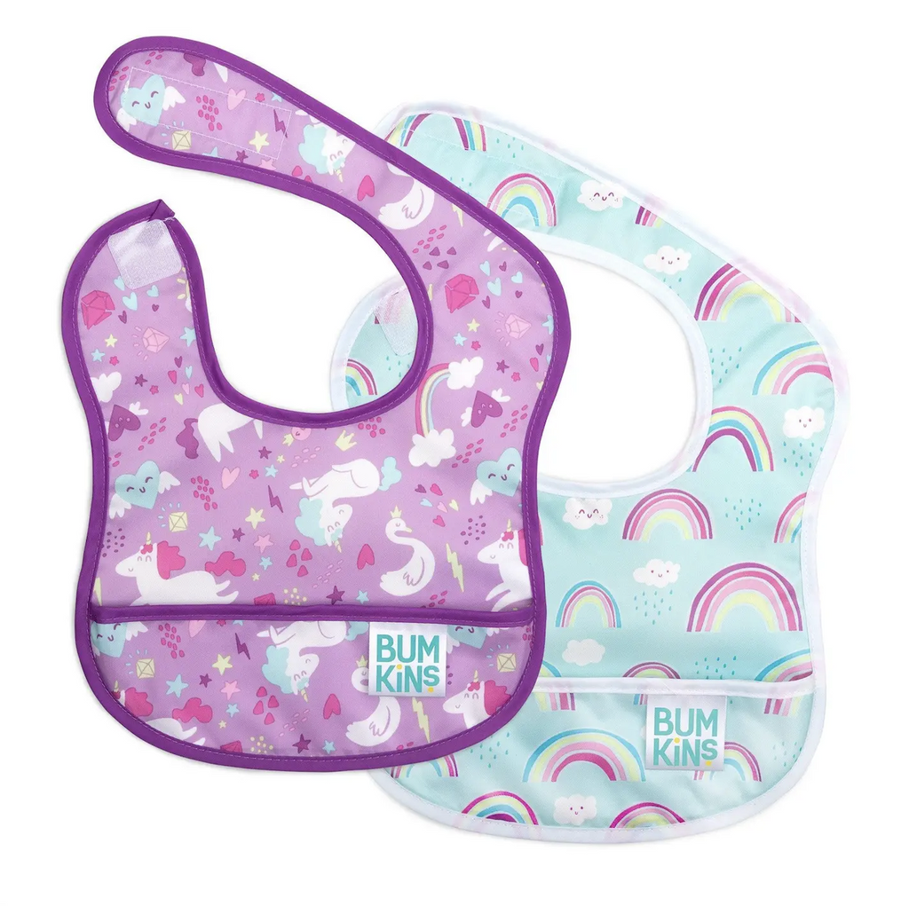 Set of 2 baby bibs with pockets along the bottom to catch food and spills. One is purple with unicorns, hearts and star. The other bib has rainbows and clouds on a blue background. 