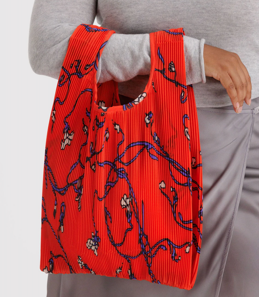 A person holding the Pleated Baggu Red Snapdragon reusable bag on their arm. 
