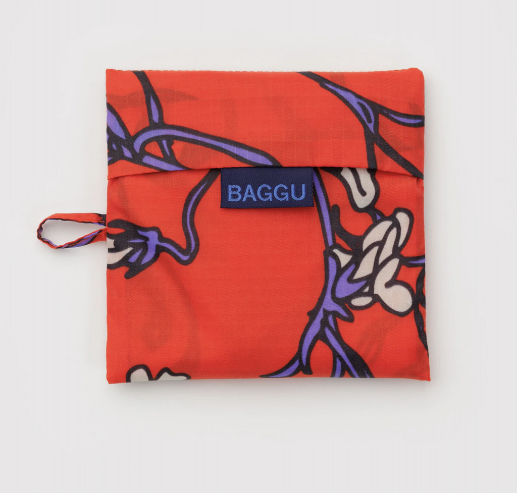 Baggu standard reusable bag folded into it's flat storage pouch in the Red Snapdragon pattern. 