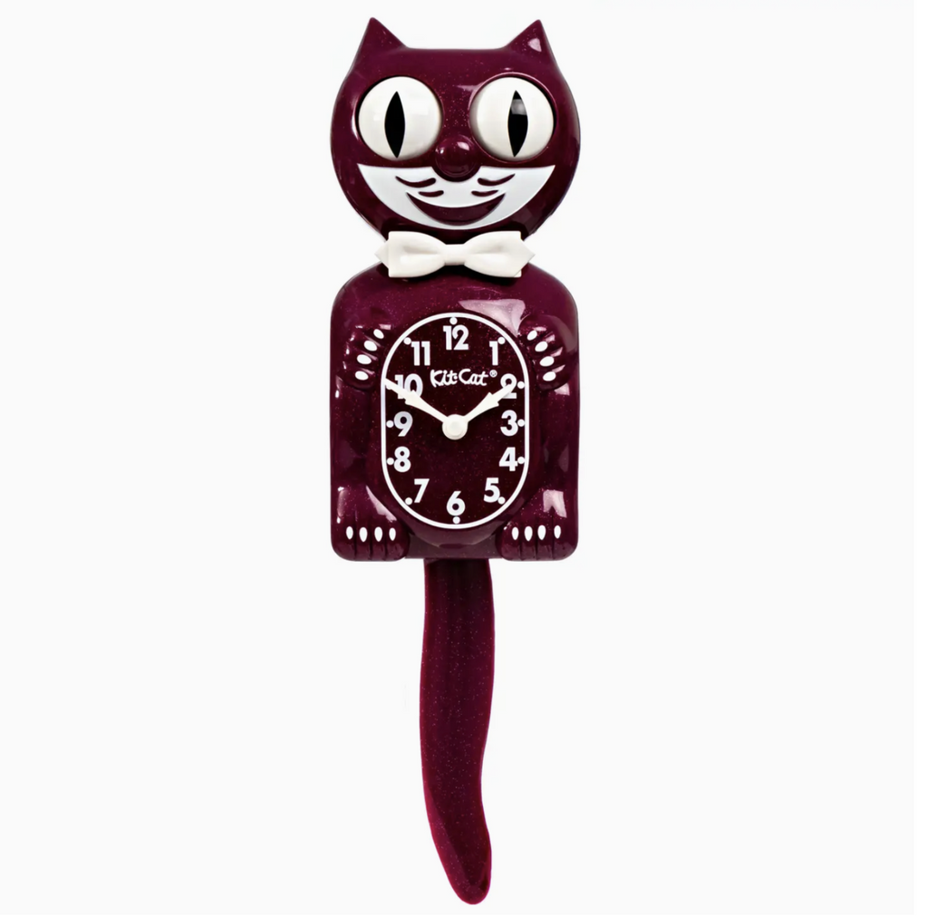 Ruby Red Kit Cat Clock is a wall mounted cat shaped clock. Cat is wearing a white bow tie, has white claws, and eyes and tail that move from side to side.