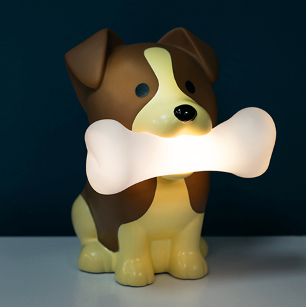 Rufus the Dog Mood Light on a table in a dimly lit room with the bone that Rufus holds in his mouth illuminated. 