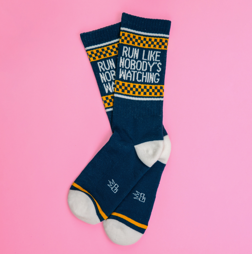 A pair of blue tube socks with white stripes and yellow and blue checkerboard that read "Run Like Nobody's Watching" in white letters. 