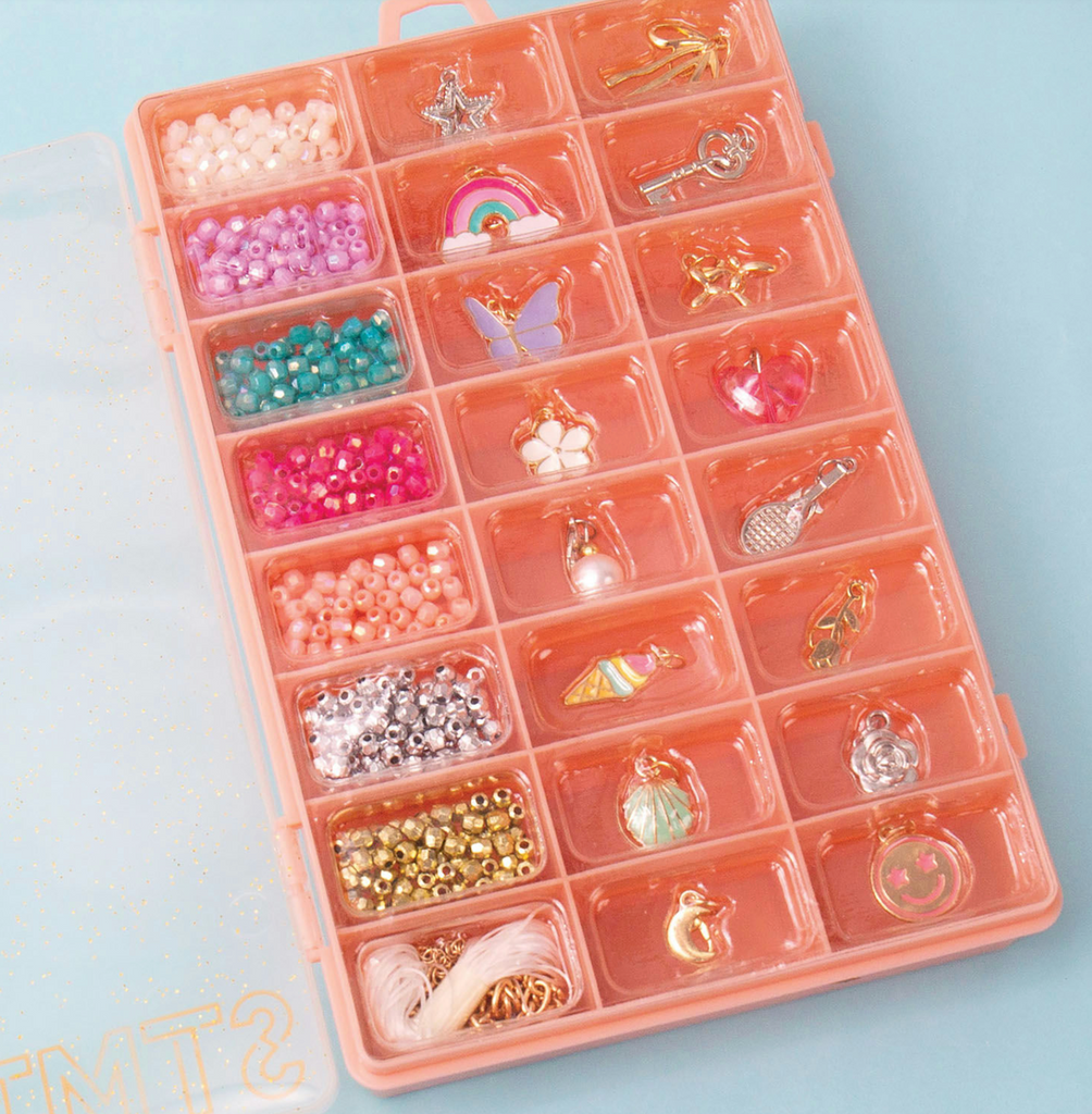 Close up picture of the storage case full of beads, charms, elastic cording, and stylish gold chains all included in the STMT Simply Charming Jewelry kit. 