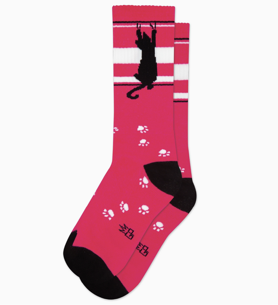 Dark pink tube socks with white and black stripes, white paw prints and a black cat scratching it's way up the top of the sock. 