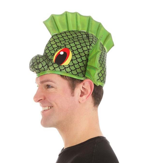 A side view of the Sea Monster Sprayzy hat with a printed scale pattern and decorated with embroidered eyes. Stiffened green fish fins stick out above each ear, and another fin forms a top crest.  A soft-sculpted snout is nestled between the eyes at the base of the hat. 