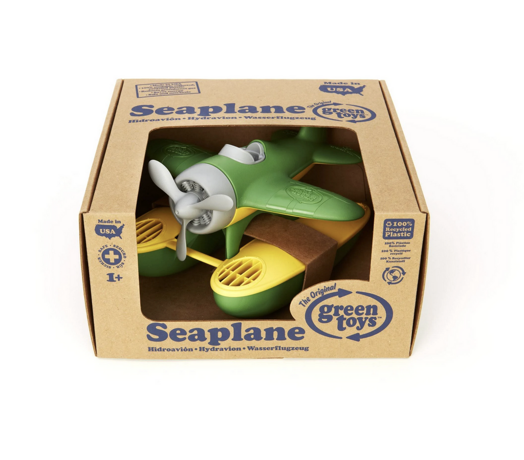 Green and yellow toy seaplane packaged in a kraft box that is open in the front so you can see the plane. 