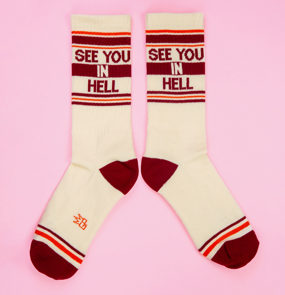 A pair of white tube socks with brown and orange stripes that read "See You In Hell"