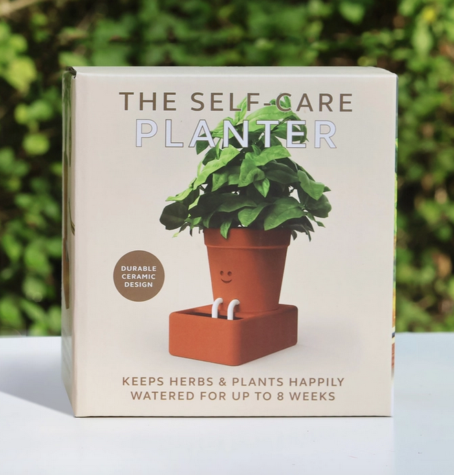 A  beige box with a picture of the Self Care Planter with it's rope feet dipped in the water resorvoir. The box reads " Keeps Herbs and Plants Happily Watered for Up To 8 Weeks"