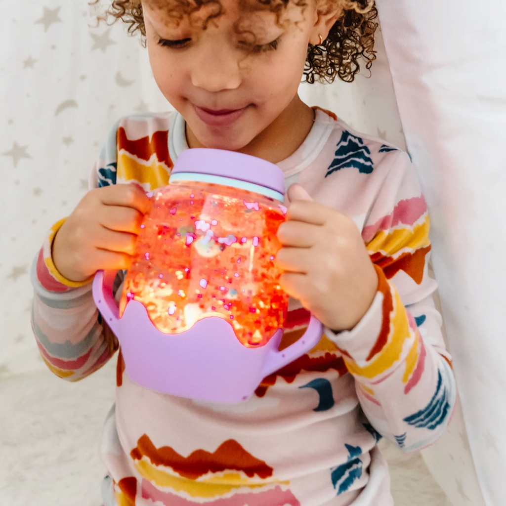 Purple Sensory Jar lit up, filled with water and orange beads.