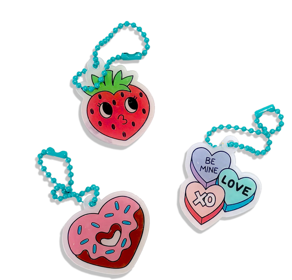 Shrink-it charms of a cute strawberrry, heart shaped donut and candy hearts that read love, be mine, and xo's, attached to a chain. 