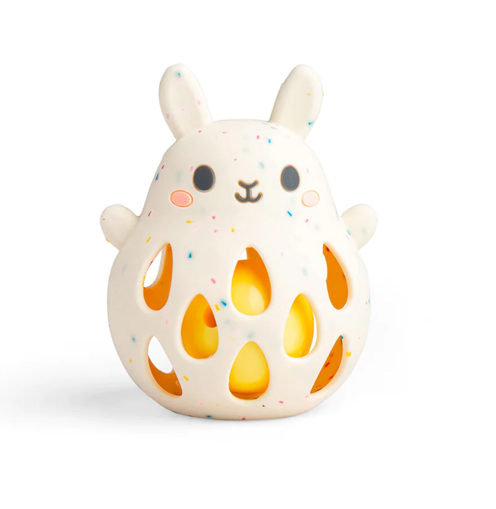 Silicone Bunny Rattle. White with multicolored specks throughout with teardrop shaped holes in the bunnys tummy showing a yellow ball which makes the rattle sound. 