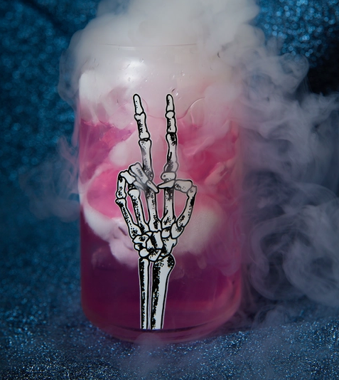 Clear Can Glass with a skeleton hand throwing the peace sign decal on the front. The glass is full of a bubbling purple potion. 