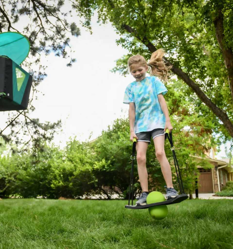 A kid jumping and riding the Skyboard Underglow in the backyard. 