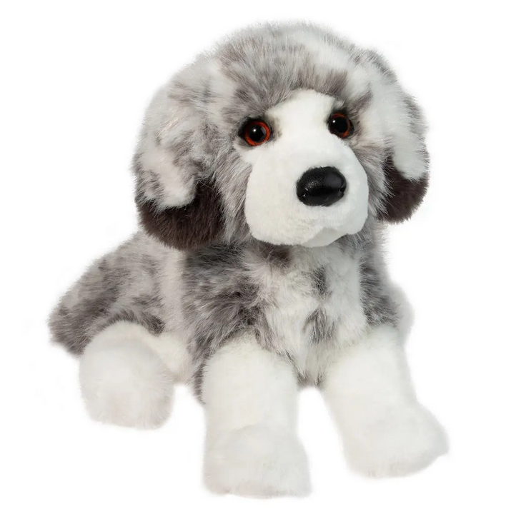 Australian Shepherd stuffed animal with the blue merle coat pattern. She is lying on her stomach with her head facing forward and white socked paws out in front.