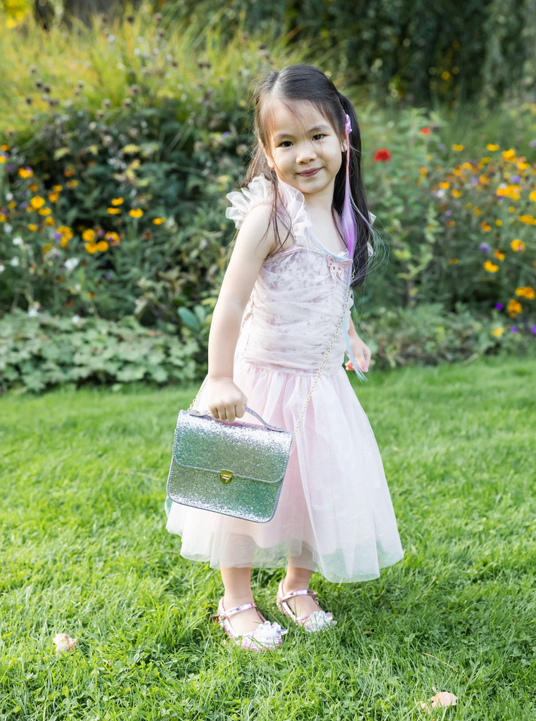 A young girl dressed in a party dress carrying the Skyline Sparkle Party Purse. 