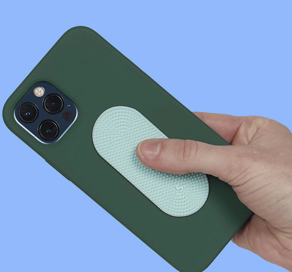 A hand holding a cell phone with the Slabs Static Oval sensory sticker attached to the back of it. 