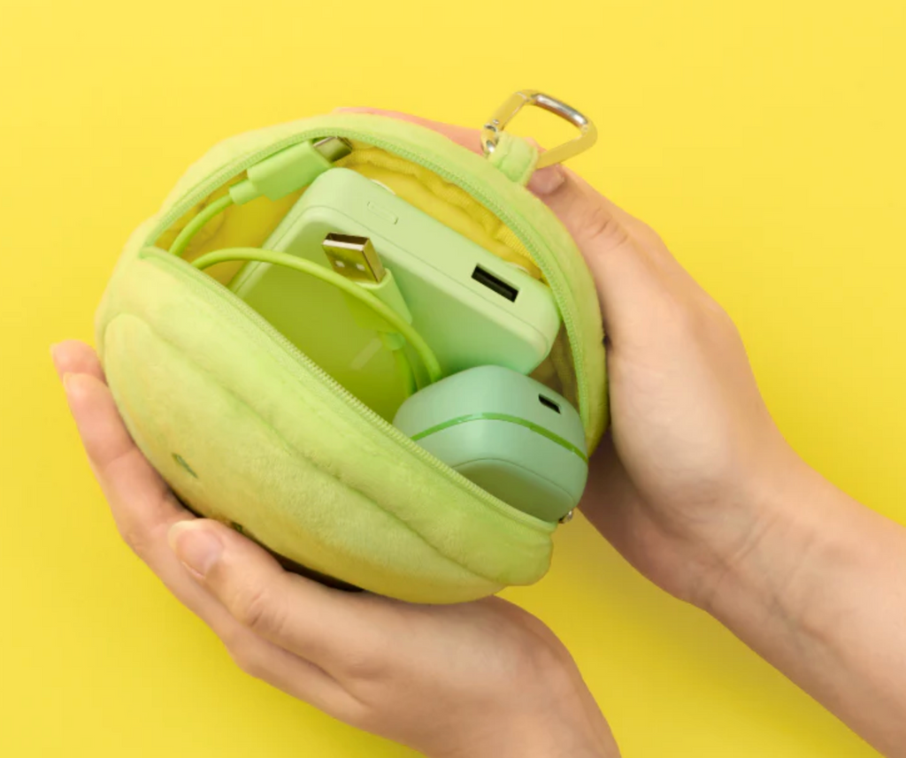 Green plush case with phone and headphones inside, held by hands against a yellow background