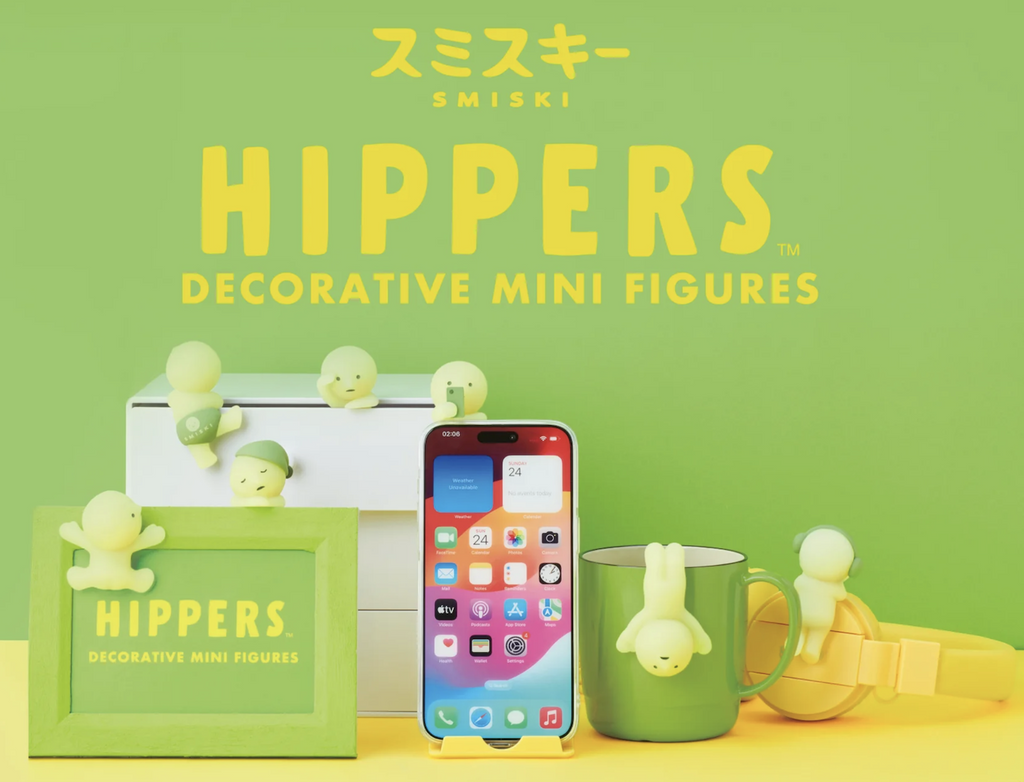 Smiski vinyl figures hanging off of a phone, cup, box, and picture frame.