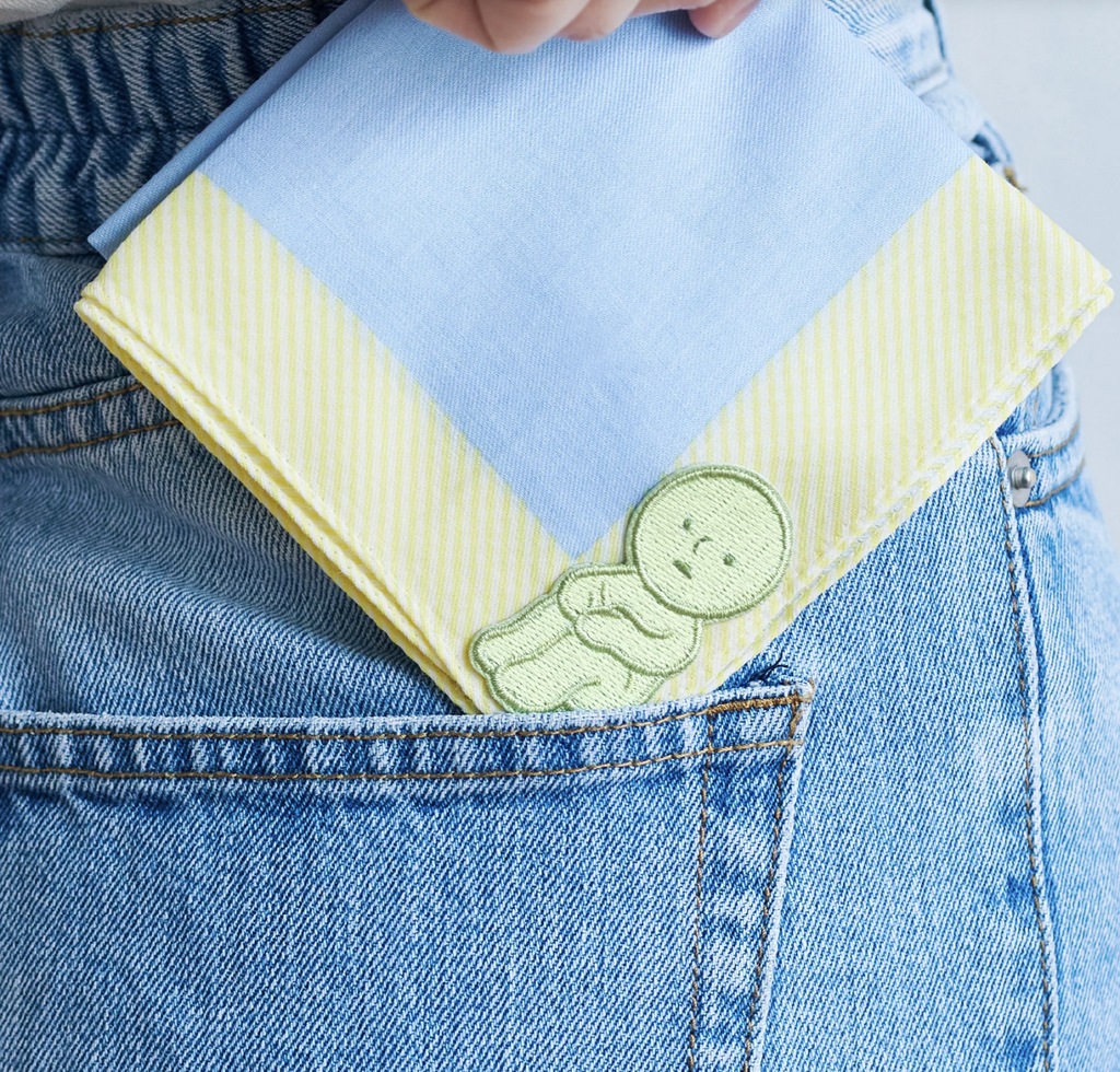 Smiski Hugging Knees Embroidered Sticker on a bandana near a jean pocket.