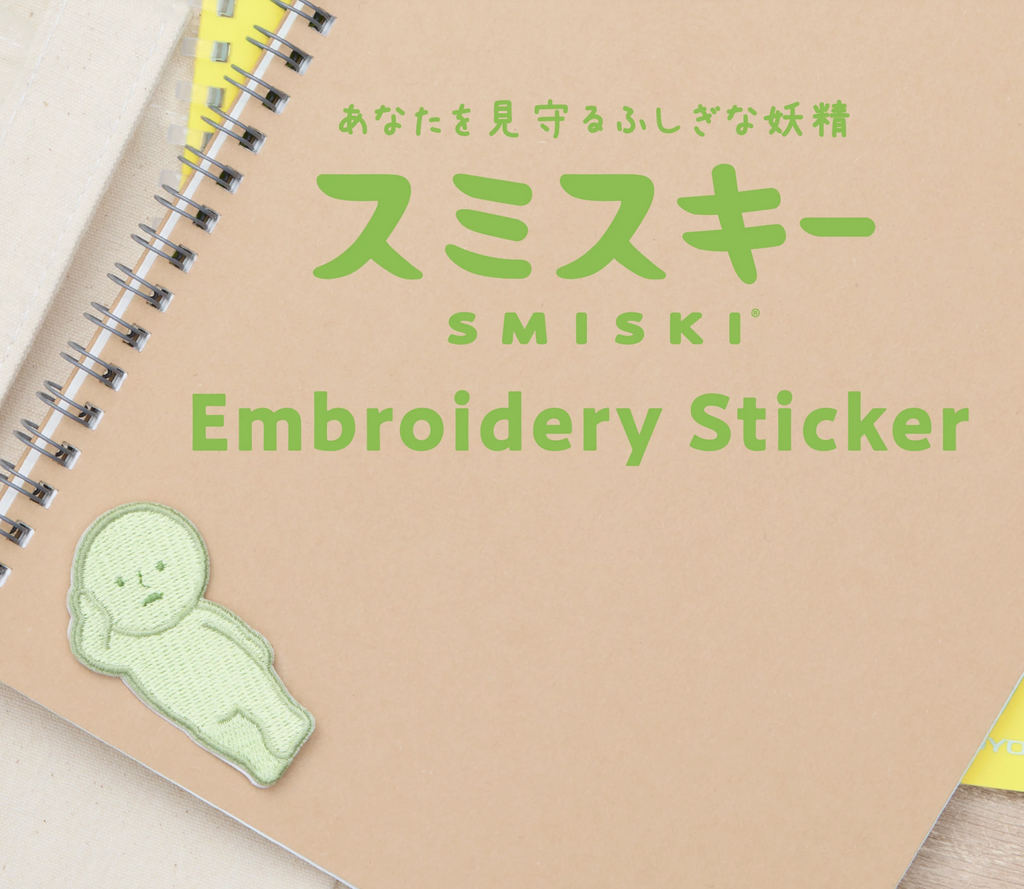 Smiski lounging embroidered sticker on a notebook.